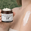 Person holding a jar of Grassfed Tallow Co. whipped tallow face and body cream with a visible application on skin.