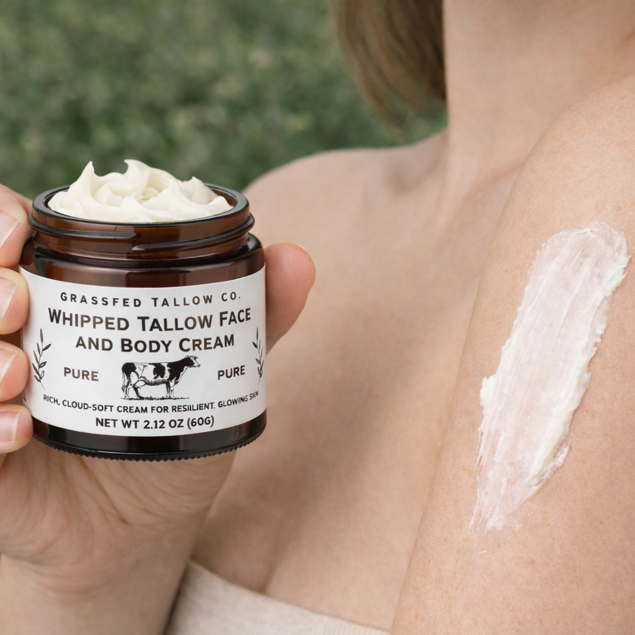 Person holding a jar of Grassfed Tallow Co. whipped tallow face and body cream with a visible application on skin.
